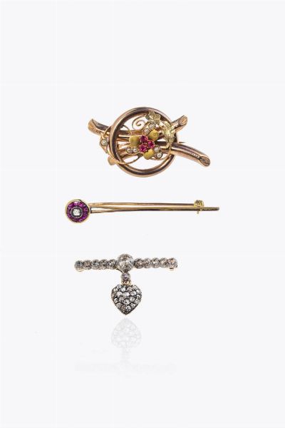 LOTO DI TRE SPILLE : - in oro giallo a bassa caratura ed argento  a barretta  con cuore pendente apribile con contenitore porta capelli o foto  interamente in rosette  diamanti taglio vecchio e 8/8 per totali ct 0 45. Peso gr 5 4 -in oro giallo  a barretta  con rubini sintetici e una rosetta di ct 0 10 ca. Peso gr 3 -in oro rosa a bassa caratura  XIX secolo  a volute con perline e rubini sintetici. Peso gr 4 3  - Asta Asta 205 Gioielli - Associazione Nazionale - Case d'Asta italiane