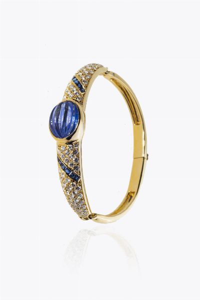 BRACCIALE : Peso gr 30 rigido in oro giallo con al centro zaffiro cabochon fesonato di ct 6 50 ca; diamanti taglio brillante per totali ct 3 0 ca  probabile colore G-H  purezza IF-VVS e due fasce in zaffiri taglio carr per totali ct ca  - Asta Asta 205 Gioielli - Associazione Nazionale - Case d'Asta italiane