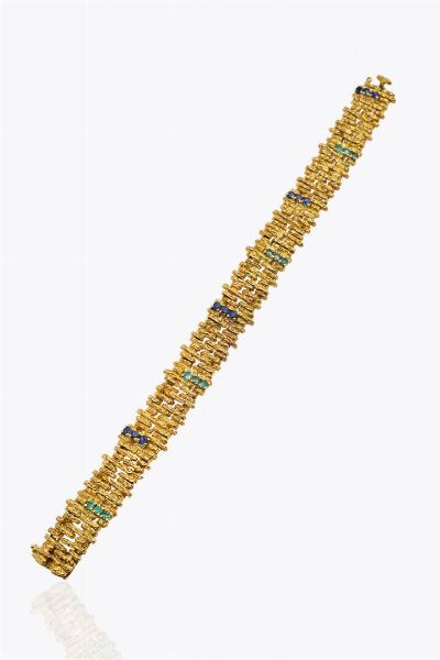BRACCIALE : Peso gr 48 4 Lunghezza cm18 in oro giallo  lavorato a segmenti rigidi decorati a corteccia con inserti in smeraldi e zaffiri taglio rotondo per totali ct ca  - Asta Asta 205 Gioielli - Associazione Nazionale - Case d'Asta italiane