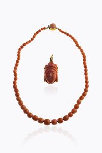 LOTTO DI DUE GIOIELLI - -ciondolo in oro giallo con corallo cabochon nei toni del salmone con inciso il volto di un orientale. Peso gr  [..]