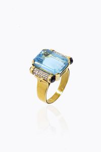 ANELLO - Peso gr 16 4 Misura 25 (65) in oro giallo  sommit a voluta con al centro grande topazio azzurro ed ai lati quattro  [..]