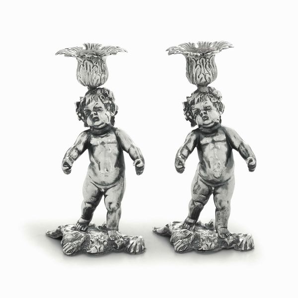 Coppia di candelieri in argento fuso, sbalzato e cesellato. Europa centrale XX secolo. Argentiere C. Waschmann. Marchio d'importazione francese  - Asta Argenti del XX secolo - Associazione Nazionale - Case d'Asta italiane