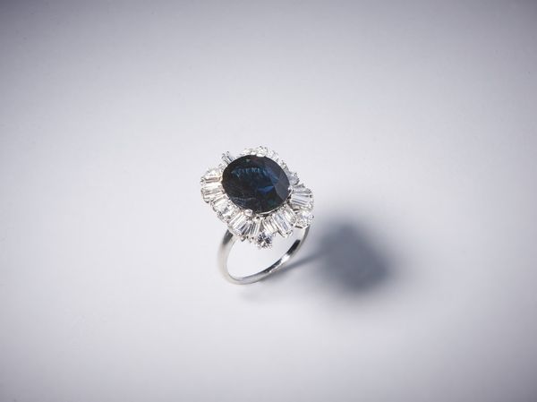 . : Anello artigianale in oro bianco 750/1000 con diamanti bianchi taglio a brillante per tot. 1,50 ct circa e diamanti bianchi taglio a baguette di 3,50 ct circa con zaffiro blu centrale 7,50 ct circa.  - Asta Asta 366 | GIOIELLI - OROLOGI - Giunonicae Online - Associazione Nazionale - Case d'Asta italiane