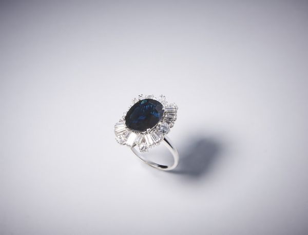 . : Anello artigianale in oro bianco 750/1000 con diamanti bianchi taglio a brillante per tot. 1,50 ct circa e diamanti bianchi taglio a baguette di 3,50 ct circa con zaffiro blu centrale 7,50 ct circa.  - Asta Asta 366 | GIOIELLI - OROLOGI - Giunonicae Online - Associazione Nazionale - Case d'Asta italiane