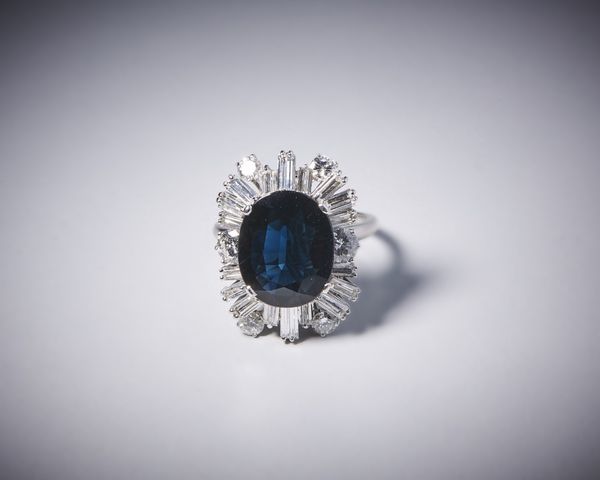 . : Anello artigianale in oro bianco 750/1000 con diamanti bianchi taglio a brillante per tot. 1,50 ct circa e diamanti bianchi taglio a baguette di 3,50 ct circa con zaffiro blu centrale 7,50 ct circa.  - Asta Asta 366 | GIOIELLI - OROLOGI - Giunonicae Online - Associazione Nazionale - Case d'Asta italiane