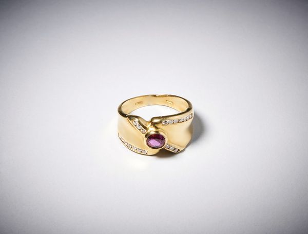 . : Anello a ''fascia'' in oro giallo  750/1000 con rubino centrale ovale di circa  0,35 carati con contorno di diamanti bianchi taglio a  brillante di circa 0,40 carati circa.  - Asta Asta 366 | GIOIELLI - OROLOGI - Giunonicae Online - Associazione Nazionale - Case d'Asta italiane