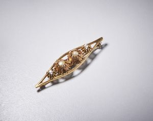 . - Spilla a losanga, con quattro fiori geometrici, in oro giallo 750/1000 con due diamanti bianchi di taglio vecchio a cuscino di 0,30 ct totali circa e due piccole perle mab�.