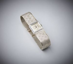 . - Orologio in oro bianco.750/1000 di forma rettangolare ''Incabloc'' con maglia tessita.