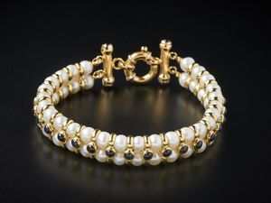 . - Bracciale di perle coltivate bianche 5.20 mm con struttura in oro giallo 750/1000 e piccoli zaffiri blu taglio cabochon.