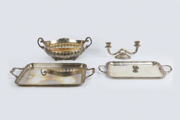 LOTTO DI QUATTRO OGGETTI IN ARGENTO : Peso complessivo gr 3169 8 Composto da: - 1 centrotavola di forma ovale con manici a volute; corpo bombato e lavorato. Poggiante su quattro piedini. Peso gr 793 8 - 2 vassoi di diversa forma e misura con manici. Peso gr 2127 4 - 1 candeliere a due luci. Peso gr 248 6  - Asta Antiquariato, Argenti, Dipinti e Sculture - Associazione Nazionale - Case d'Asta italiane