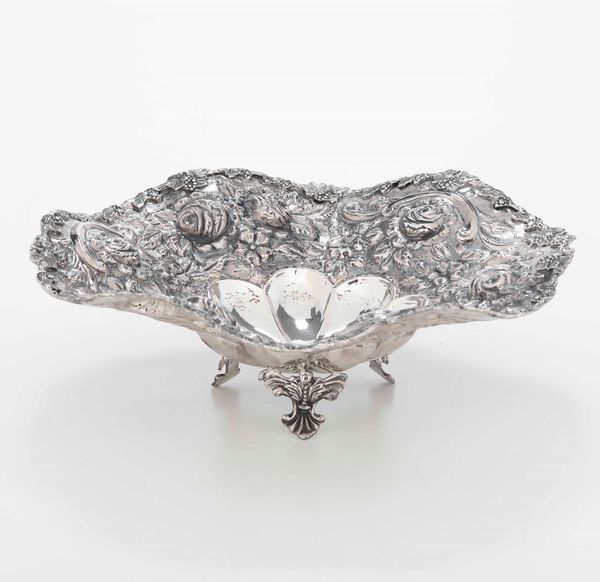 Centrotavola in argento fuso, sagomato e cesellato, con bordo mistillineo sbalzato a rose. Manifattura del XX secolo.  - Asta Argenti - Associazione Nazionale - Case d'Asta italiane