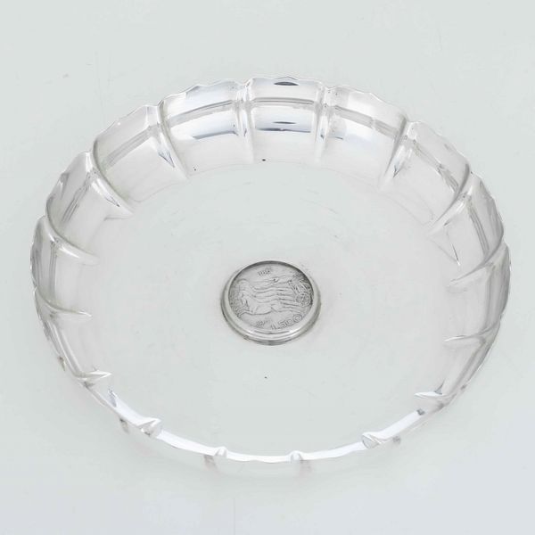 Piattino in argento sterling con moneta 500 lire. Argenteria artistica milanese del XX secolo. Argentiere AUGE per gioielleria Zendrini  - Asta Argenti - Associazione Nazionale - Case d'Asta italiane