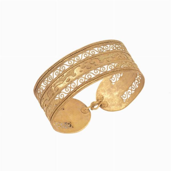 BRACCIALE RIGIDO STILE ARCHEOLOGICO MICROGRANULATOin oro giallo 18kt, raffigurante un fregio decorativo traforato e lavorato con la tecnica della granulazione, dim. cm 6,5x6 circa, gr. 34  ARCHAELOGICAL STYLE MICRO-GRANULATED BANGLE IN 18KT YELLOW GOLD  - Asta Importanti maioliche rinascimentali  - Associazione Nazionale - Case d'Asta italiane