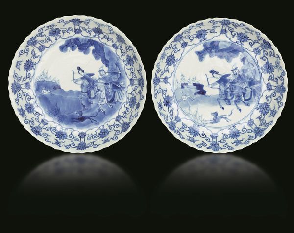 Coppia di piatti in porcellana bianca e blu con scene di caccia e decori floreali, Cina, Dinastia Qing, epoca Kangxi (1662-1722)  - Asta Fine chinese works of art - Associazione Nazionale - Case d'Asta italiane