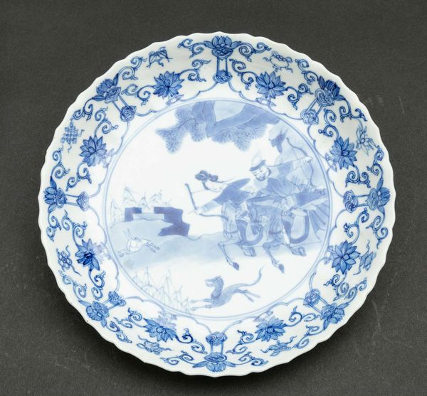 Coppia di piatti in porcellana bianca e blu con scene di caccia e decori floreali, Cina, Dinastia Qing, epoca Kangxi (1662-1722)  - Asta Fine chinese works of art - Associazione Nazionale - Case d'Asta italiane