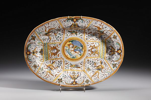 MANIFATTURA DI DERUTA : Piatto ovale in maiolica policroma decorato con putto alato a riposo entro medaglione circolare contornato da decori a grottesche e a volute  - Asta Asta 379 | ARTE ANTICA E DEL XIX SECOLO - Dipinti antichi e antiquariato  Online - Associazione Nazionale - Case d'Asta italiane