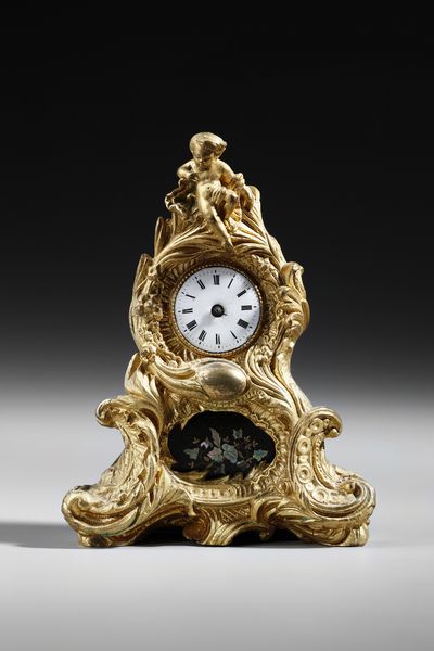 MANIFATTURA FRANCESE DEL XIX SECOLO : Piccolo orologio da tavolo in bronzo dorato in stile Luigi XV, ornato da volute e decorazioni floreali, sormontato da una figura di putto  - Asta Asta 379 | ARTE ANTICA E DEL XIX SECOLO - Dipinti antichi e antiquariato  Online - Associazione Nazionale - Case d'Asta italiane