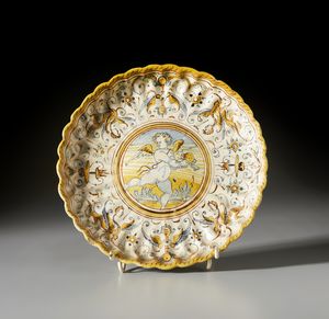 MANIFATTURA DI FAENZA DEL XVI-XVII SECOLO - Crespina in maiolica policroma decorata con putto alato entro medaglione circolare contornato da decori a raffaellesche