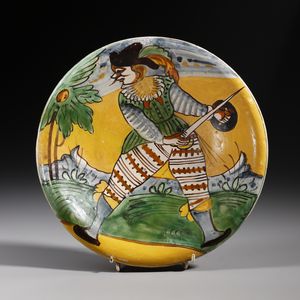 MANIFATTURA DI MONTELUPO DEL XVII SECOLO - Piatto in maiolica policroma raffigurante armigero in un paesaggio con montagne e un albero da frutto