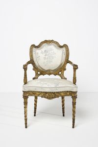 MANIFATTURA DEL XVIII-XIX SECOLO - Poltrona in legno dorato e intagliato, schienale a scudo contornato da decorazione a fascia di alloro, braccioli terminanti in teste leonine, gambe a faretra con decorazione a pampini e grappoli d'uva