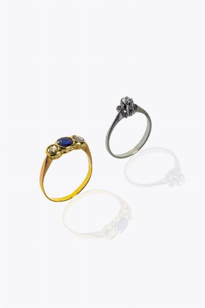 LOTTO DI DUE ANELLI : - in oro bianco con solitario di  ct 0 10 ca. Peso gr 2 3. Misura 13 (53) -in oro giallo  modello trilogy con due rosette per totali ct 0 25 ca e uno zaffiro taglio rotondo di ct 0 45 ca. Peso gr 2 3. Misura 20 (60)  - Asta Gioielli - Associazione Nazionale - Case d'Asta italiane