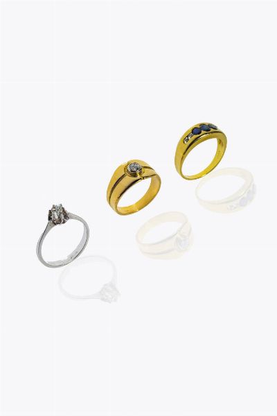 LOTTO DI TRE ANELLI : -in oro bianco con diamante centrale di vecchio taglio di ct 0 15 ca Peso gr 2 2. Misura 12 (52) -in oro giallo  a fascia  al centro diamante di ct 0 20 . Peso gr 4 9. Misura 11 (51) -in oro giallo con tre zaffiri taglio ovale per totali ct 0 80 ca e quattro diamanti taglio brillante per totali ct 0 05. Peso gr 4. Misura 12 (52)  - Asta Gioielli - Associazione Nazionale - Case d'Asta italiane