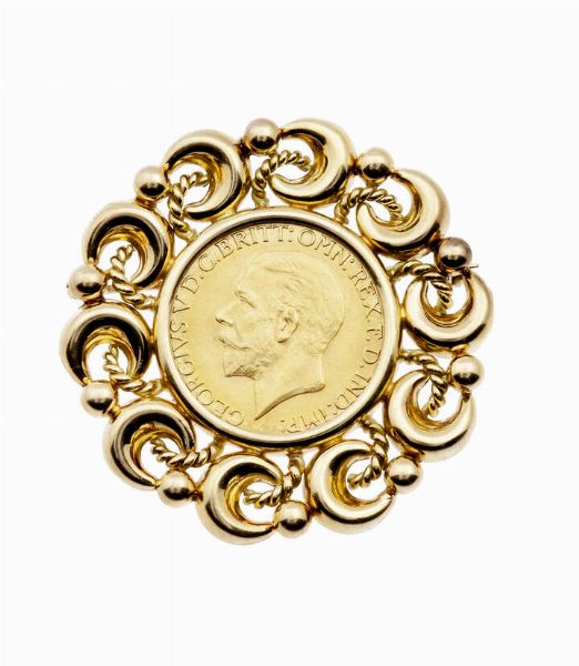SPILLA : in oro giallo con al centro una Sterlina  circondata da bordo a mezzelune. Peso gr 15 8  - Asta Gioielli - Associazione Nazionale - Case d'Asta italiane