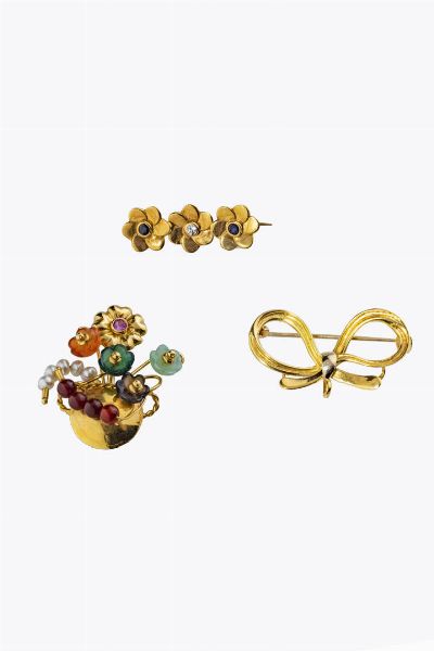 LOTTO DI TRE SPILLE : in oro giallo: -a forma di fiocco. Peso gr 5 5. Cm 2x3 -a forma di barretta con tre fiori stilizzati. Peso gr 2 4. Lunghezza cm 3 -a forma di vaso fiorito con fiori in pietre fini. Peso gr 5 8. Cm 3 5x3  - Asta Gioielli - Associazione Nazionale - Case d'Asta italiane