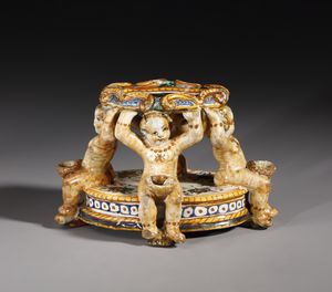 BOTTEGA DEI PATANAZZI, URBINO, FINE DEL XVI SECOLO : Saliera in maiolica policroma poggiante su base ovale su cui si trovano quattro putti seduti che sorreggono l'invaso superiore, decorato nell'incavo da una figura allegorica in grisaille  - Asta Asta 387 | ARTE ANTICA E DEL XIX SECOLO - DAL RINASCIMENTO AL SIMBOLISMO: OPERE DA COLLEZIONI ITALIANE Tradizionale - Associazione Nazionale - Case d'Asta italiane