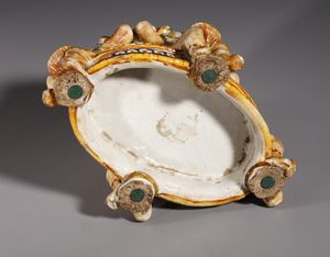 BOTTEGA DEI PATANAZZI, URBINO, FINE DEL XVI SECOLO : Saliera in maiolica policroma poggiante su base ovale su cui si trovano quattro putti seduti che sorreggono l'invaso superiore, decorato nell'incavo da una figura allegorica in grisaille  - Asta Asta 387 | ARTE ANTICA E DEL XIX SECOLO - DAL RINASCIMENTO AL SIMBOLISMO: OPERE DA COLLEZIONI ITALIANE Tradizionale - Associazione Nazionale - Case d'Asta italiane
