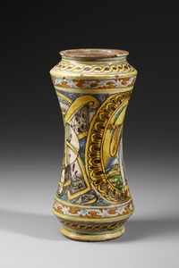 MANIFATTURA DI COLLESANO DEL XVII SECOLO : Albarello in maiolica policroma di forma a rocchetto, sul fronte figura di santa martire entro medaglione ovale su fondo giallo, contornato da decori a trofei su fondo blu  - Asta Asta 387 | ARTE ANTICA E DEL XIX SECOLO - DAL RINASCIMENTO AL SIMBOLISMO: OPERE DA COLLEZIONI ITALIANE Tradizionale - Associazione Nazionale - Case d'Asta italiane