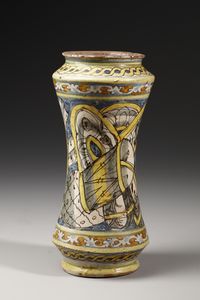 MANIFATTURA DI COLLESANO DEL XVII SECOLO : Albarello in maiolica policroma di forma a rocchetto, sul fronte figura di santa martire entro medaglione ovale su fondo giallo, contornato da decori a trofei su fondo blu  - Asta Asta 387 | ARTE ANTICA E DEL XIX SECOLO - DAL RINASCIMENTO AL SIMBOLISMO: OPERE DA COLLEZIONI ITALIANE Tradizionale - Associazione Nazionale - Case d'Asta italiane