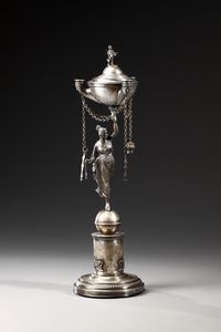 ARGENTIERE ROMANO DEL XIX SECOLO - Lucerna in argento raffigurante figura femminile su sfera, base a colonna su appoggio di forma circolare, vaschetta a tre beccucci in forma di teste umane