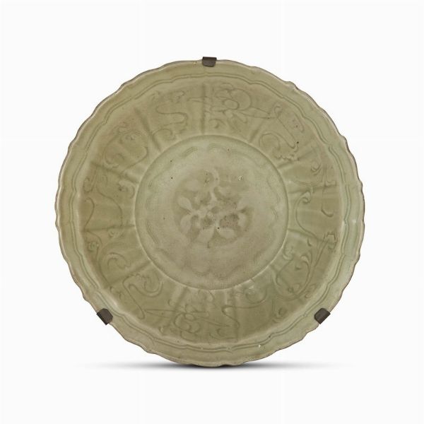 PIATTO, CINA, DINASTIA MING, SEC. XV�����������������������������������������������������������������������������������������������������������������������������������������������������������������������������   in porcellana verde celadon Longquan decorato con fiori nel centro, bordo mosso a forma di fiore decorato con i fiori stilizzati incisi.������������������������������������������������������������������������������������������������������������������������������������������������������������������������������������������������������������� Diam.cm 33������������������������������������������������������������������������������������������������������������������������������������������������������������������������������������������������������ 明 十五世纪 龙泉青瓷刻花纹葵口盘���  - Asta Arte Orientale | 东方艺术 - Associazione Nazionale - Case d'Asta italiane