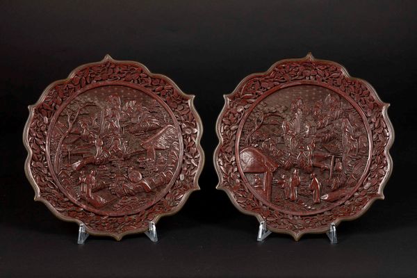 Coppia di piatti in lacca rossa con decoro a rilievo di saggi entro paesaggio, Cina, Dinastia Qing, XIX secolo  - Asta Arte Orientale - Associazione Nazionale - Case d'Asta italiane