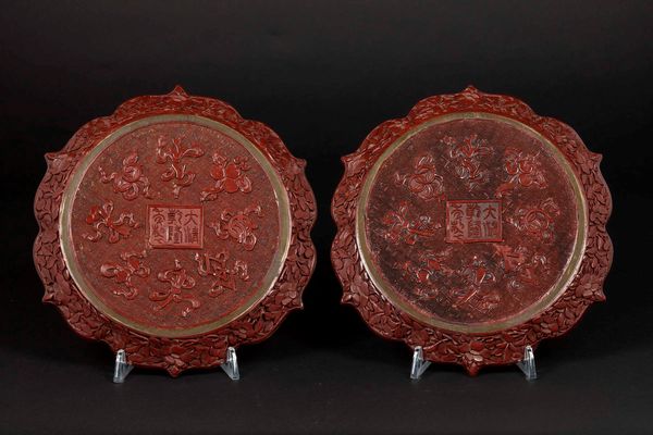 Coppia di piatti in lacca rossa con decoro a rilievo di saggi entro paesaggio, Cina, Dinastia Qing, XIX secolo  - Asta Arte Orientale - Associazione Nazionale - Case d'Asta italiane