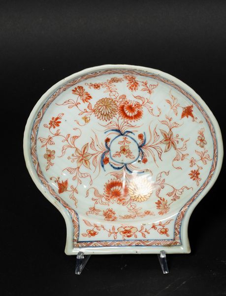Piccolo piatto a foggia di conchiglia in porcellana Imari con decori floreali, Cina, Dinastia Qing, epoca Kangxi (1662-1722)  - Asta Arte Orientale - Associazione Nazionale - Case d'Asta italiane