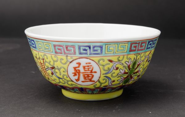 Piccola ciotola in porcellana a smalti policromi con simboli taoisti, fiori di loto e motivo a greca su fondo giallo, Cina, XX secolo  - Asta Arte Orientale - Associazione Nazionale - Case d'Asta italiane