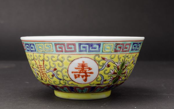 Piccola ciotola in porcellana a smalti policromi con simboli taoisti, fiori di loto e motivo a greca su fondo giallo, Cina, XX secolo  - Asta Arte Orientale - Associazione Nazionale - Case d'Asta italiane