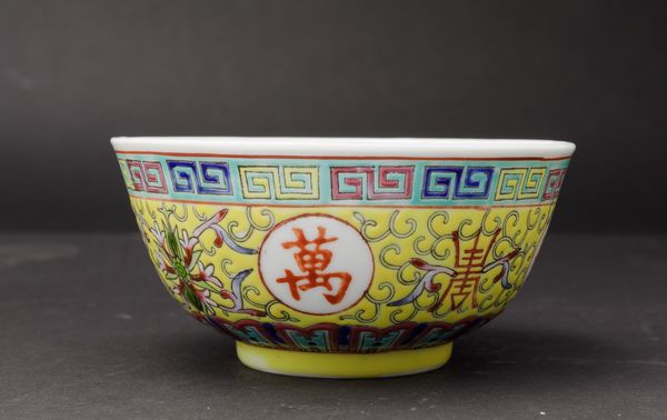 Piccola ciotola in porcellana a smalti policromi con simboli taoisti, fiori di loto e motivo a greca su fondo giallo, Cina, XX secolo  - Asta Arte Orientale - Associazione Nazionale - Case d'Asta italiane