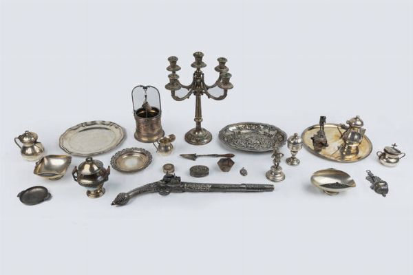 LOTTO DI VENTUNO OGGETTI IN ARGENTO : Peso netto gr 3650 2 composto da: - un fucile ornamentale lavorato e inciso a motivi vegetali Peso gr 593 - un portapastiglie tondo Peso gr 16.9 - una tabacchiera di forma ovale sblazata con figura di contadina e mucche Peso gr 55.9 - due alzate di varie forme e misure Peso gr 230.7 - un ciondolo di forma ovale in argento 900/100 Peso gr 9.3 - una ciotolina di forma esagonale con manici non in argento Peso gr 32.7 - un acquasantiera piccola Peso gr 53.1 - ciotolina con due manici lavorata a volute Peso gr 39.8 - piccolo pozzo ornamentale Peso gr 430.7 - tre piatti di varie forme e misure Peso gr 747.5 - piccola cazzuola con manico in legno Peso lordo 48.5 - piccola scultura raffigurante fanciullo con cestra e bastone poggiante su base con piedi leonini Peso gr 103.3 (controlla punzoni) - zuccheriera corpo bombato  decorata con fascia a motivi vegetale  coperchio con presa a ghirlanda e manici con elementi in legno Peso gr 236.2 - piccola pisside Peso gr 81.4 (controlla punzoni) - piccolo servizio in argento composto da: teiera  caffettiera  zuccheriera e lattiera Peso gr 614.9 - vassoio di forma ovale sbalzato con scena di guerra Peso gr 315.8 - una sculturina raffigurante maschera carnevalesca firmata Gino Bottazzo Peso gr 143.0 - candeliere a cinque luci decorato a motivi geomentrici. Base circolare in legno Peso lordo 899.6  - Asta  Dipinti, argenti e antiquariato - Associazione Nazionale - Case d'Asta italiane