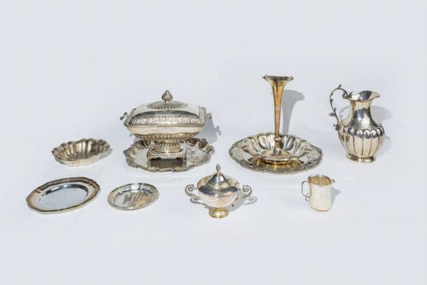 LOTTO DI  11 OGGETTI IN ARGENTO : Peso complessivo gr 6450 1 composto da: -1 zuccheriera con coperchio. Peso gr 279 8 -1 lattiera. Peso gr 128 6 -1 vaso soliflore  Punzoni citt di Birmingham. Peso gr 165 8 .-1 brocca. Peso gr 873 5 -2 piattini di varia forma  emisura con bordo mosso. Peso gr 333 1 -2 ciotole di varia forma e misura. Peso gr 400 4 -1 centrotavola di forma rettangolare con coperchio; presa a pigna; corpo bombato e sbalzato a motivi geometrici e vegetali. Peso gr 2311 5 -1 piatto con bordo cesellato e mosso impreziosito da gemme marroni. Peso gr 995 0. Diam. 35 cm.  -1 vassoio di forma rotonda con bordo mosso sbalzato a motivi vegetali. Peso gr 964 4. Diam. cm 34. -  - Asta  Dipinti, argenti e antiquariato - Associazione Nazionale - Case d'Asta italiane