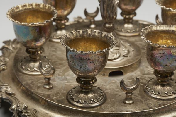 ARGENTIERE INGLESE DEL XIX SECOLO : Portauova in argento cesellato composto da 6 coppette e 4 cucchiaini, su vassoio circolare a decorazioni fitomorfe  - Asta Asta 395 | ARTE ANTICA E DEL XIX SECOLO Online - Associazione Nazionale - Case d'Asta italiane