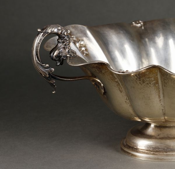 ARGENTIERE ITALIANO DEL XX SECOLO : Alzata centrotavola in argento con bordo mistilineo e decorazioni vegetali a rilievo, manici in forma di delfini, poggiante su base ovale  - Asta Asta 395 | ARTE ANTICA E DEL XIX SECOLO Online - Associazione Nazionale - Case d'Asta italiane