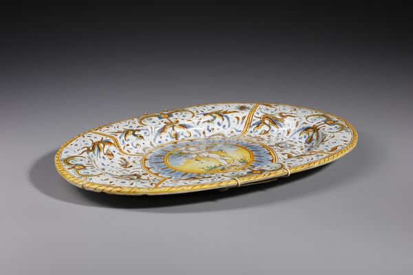 MANIFATTURA DI DERUTA : Piatto ovale in maiolica policroma decorato con putto alato armato di arco entro medaglione circolare contornato da decori a raffaellesche  - Asta Asta 395 | ARTE ANTICA E DEL XIX SECOLO Online - Associazione Nazionale - Case d'Asta italiane