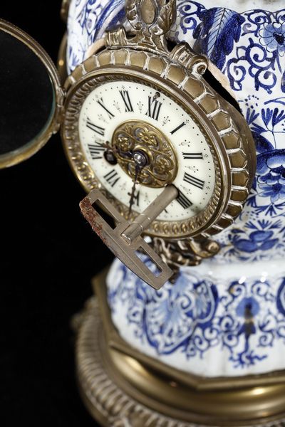 MANIFATTURA DEL XIX SECOLO : Trittico da camino in porcellana di Delft bianca e blu con inserti e montature in bronzo dorato, composto da orologio e due candelabri a quattro luci  - Asta Asta 395 | ARTE ANTICA E DEL XIX SECOLO Online - Associazione Nazionale - Case d'Asta italiane