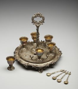 ARGENTIERE INGLESE DEL XIX SECOLO : Portauova in argento cesellato composto da 6 coppette e 4 cucchiaini, su vassoio circolare a decorazioni fitomorfe  - Asta Asta 395 | ARTE ANTICA E DEL XIX SECOLO Online - Associazione Nazionale - Case d'Asta italiane