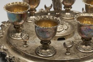 ARGENTIERE INGLESE DEL XIX SECOLO : Portauova in argento cesellato composto da 6 coppette e 4 cucchiaini, su vassoio circolare a decorazioni fitomorfe  - Asta Asta 395 | ARTE ANTICA E DEL XIX SECOLO Online - Associazione Nazionale - Case d'Asta italiane