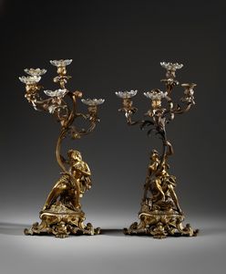 MANIFATTURA DEL XIX SECOLO - Coppia di candelieri a cinque luci in bronzo dorato in forma di figure allegoriche che sorreggono la base di un fiore