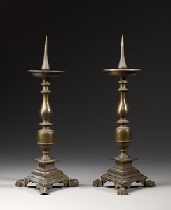 MANIFATTURA DEL XIX SECOLO - Coppia di candelieri in bronzo a rocchetto poggianti su base tripode